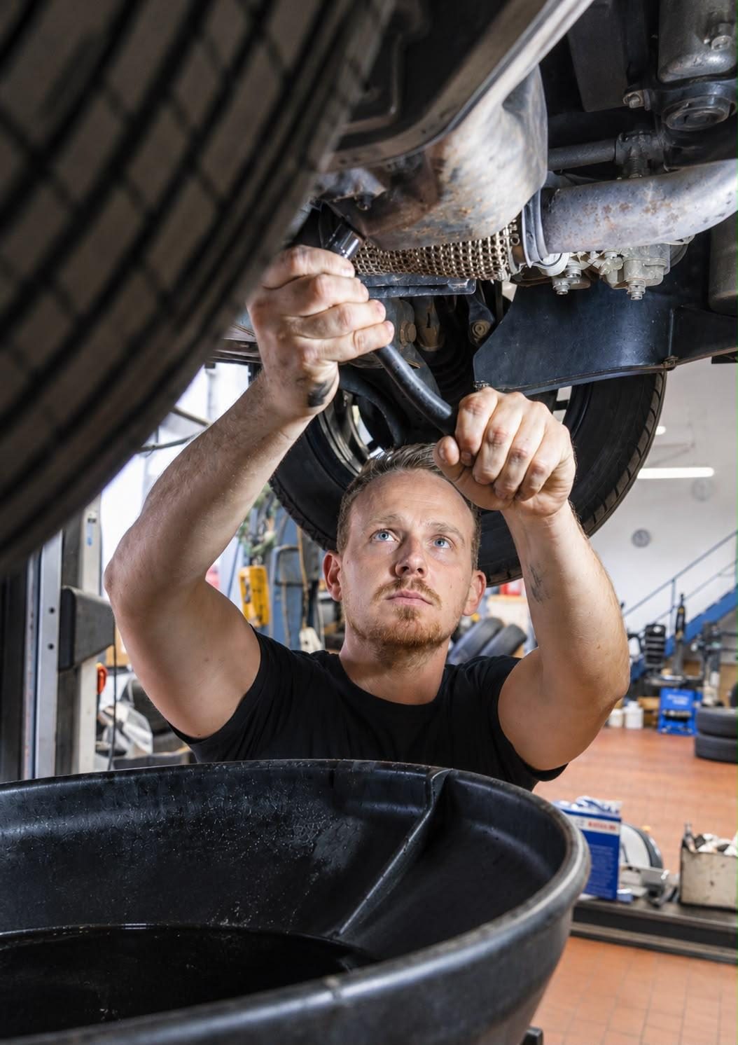 Simon Sacherer bei der Arbeit unter einem Auto in der Werkstatt von Sacherer Fahrzeugtechnik