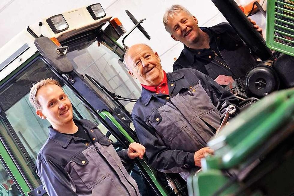 Das Team von Sacherer Fahrzeugtechnik in der Werkstatt vor einem Traktor